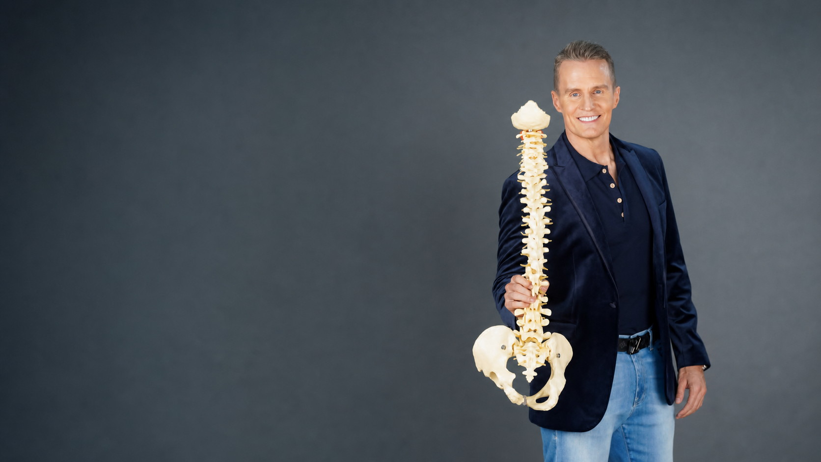 Dr Robert Walcher holding an anatomical spine model
